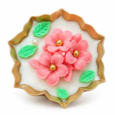 Floral urli candle with pink flowers and green leaves on a gold-edged urli