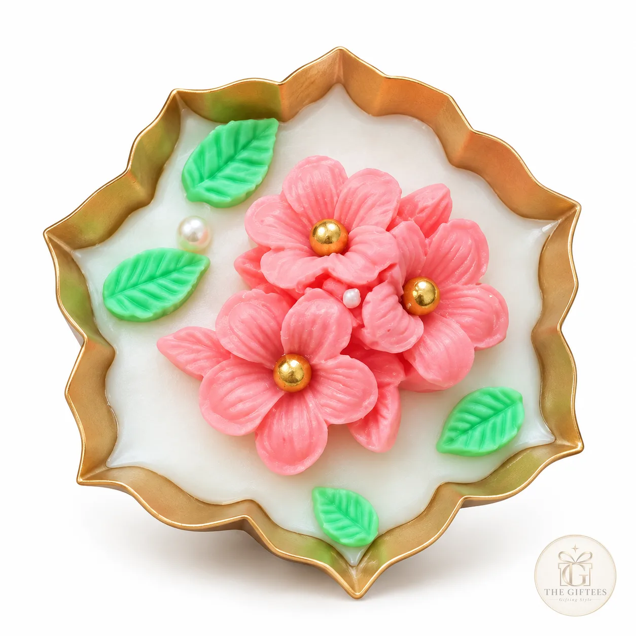 Floral urli candle with pink flowers and green leaves on a gold-edged urli